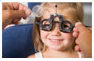 Young girl undergoing eye exam with phoropter – pediatric vision care and eye exams at Medical Eye Associates
